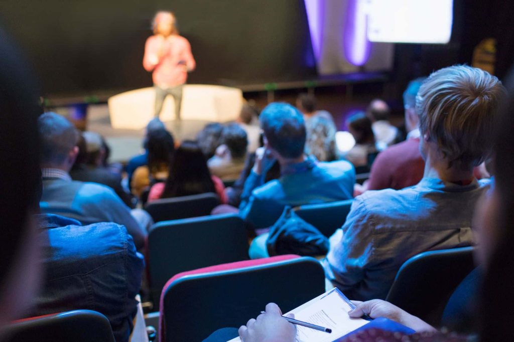 Photo of audience view of stage at conferences about how to market an event vs a conference for event planning